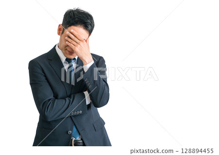 Asian middle-aged businessman in a suit holding his head in shock and stress (troubled, depressed, fatigued, laid off) Asian middle-aged businessman in a suit holding his head in shock and stress (troubled, depressed, fatigued, laid off) 128894455