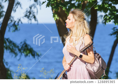 Woman playing acoustic guitar in park 128895365
