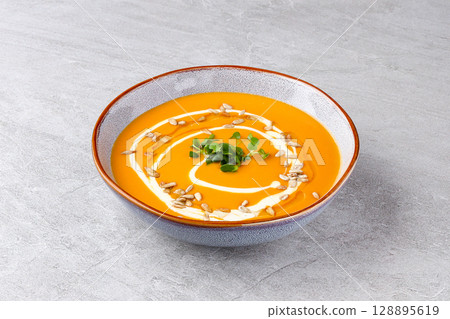 Silky Roasted Carrot Pumpkin Soup with Creamy Drizzle and Seeds 128895619