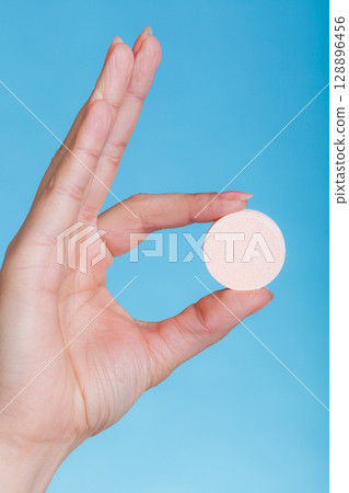 Woman hand holding big effervescent pill Woman hand holding big effervescent pill 128896456