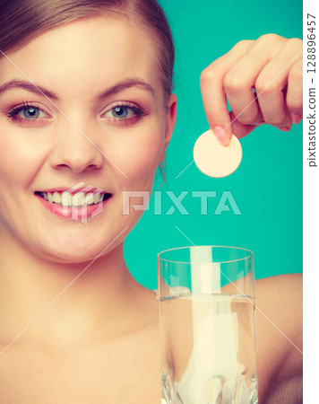 Woman holding glass with water and effervescent tablet Woman holding glass with water and effervescent tablet 128896457