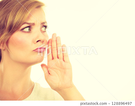 Woman whispering with hand close to mouth Woman whispering with hand close to mouth 128896497