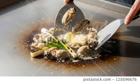 Oysters grilled on a hot plate with butter 128896676