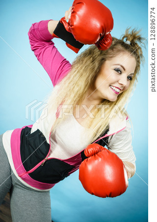Funny girl in red gloves playing sports boxing 128896774