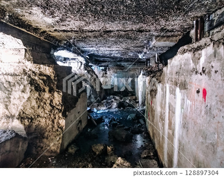 A dark, narrow tunnel with water running through it A dark, narrow tunnel with water running through it 128897304
