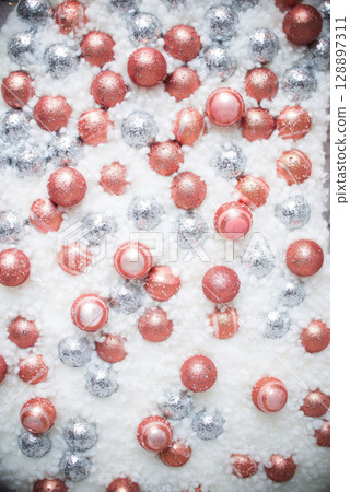 A white background with a lot of pink and silver balls. 128897311