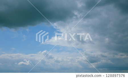 A breathtaking dynamic cloudy sky features an overcast backdrop adorned with stunning blue patches A breathtaking dynamic cloudy sky features an overcast backdrop adorned with stunning blue patches 128897376