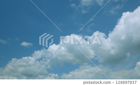 A Beautiful and Expansive Blue Sky Adorned with Fluffy Clouds Floating Gracefully 128897837