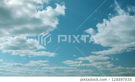 The sky is a clear blue with soft, white clouds drifting, creating a tranquil atmosphere 128897838