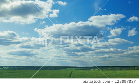 A beautiful, picturesque view of scenic skies and lush green fields under bright clouds A beautiful, picturesque view of scenic skies and lush green fields under bright clouds 128897857