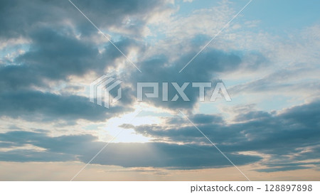 A stunningly beautiful sunset unfolds over a cloudy sky, adorned with brilliant rays of light A stunningly beautiful sunset unfolds over a cloudy sky, adorned with brilliant rays of light 128897898