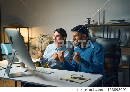 Excited Office Colleagues Celebrating Success While Working Together On A Computer Excited Office Colleagues Celebrating Success While Working Together On A Computer 128898091