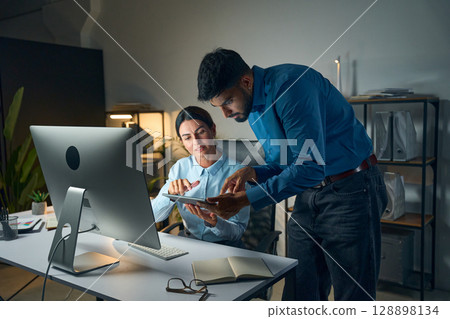 Two Colleagues Collaborating on a Project Late at Night in the Office Two Colleagues Collaborating on a Project Late at Night in the Office 128898134