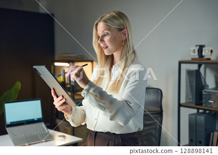 Professional Woman Working on a Tablet in a Modern Office Environment 128898141