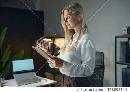 Professional Woman Using Digital Tablet In Office Workspace During Evening 128898144