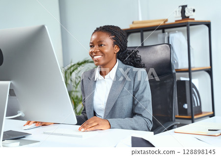 Confident Businesswoman Smiling While Working On Computer In Modern Office Environment 128898145