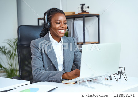 Professional Businesswoman in Headset Conducting Online Meeting in Modern Office Space 128898171