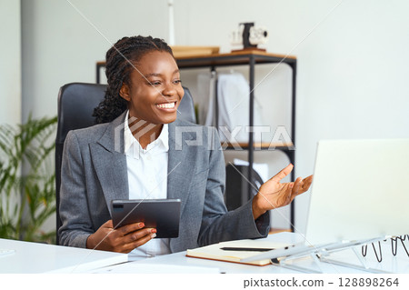 Professional Businesswoman Smiling During a Video Conference in a Modern Office Setup Professional Businesswoman Smiling During a Video Conference in a Modern Office Setup 128898264