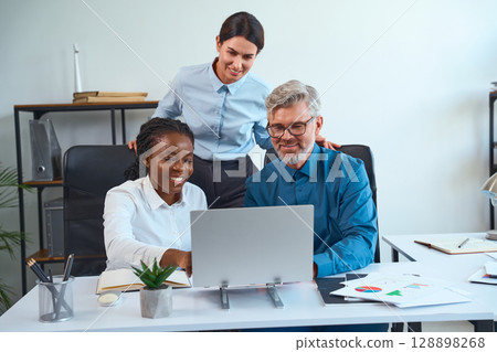 Team Collaborating at Desk Reviewing Data and Discussing Ideas in Modern Office 128898268