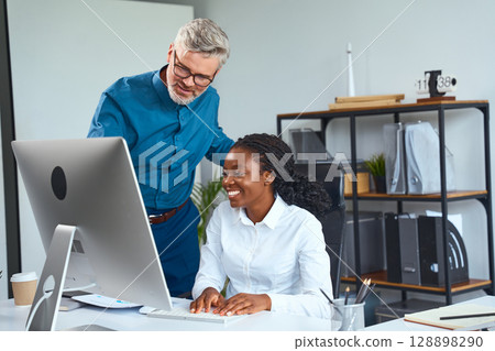 Office Team Collaboration With Smiling Professionals Working Together at a Computer Desk Office Team Collaboration With Smiling Professionals Working Together at a Computer Desk 128898290