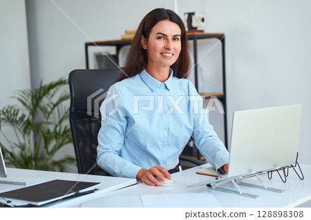 Professional Businesswoman Working At Desk With Laptop in Modern Office Environment 128898308