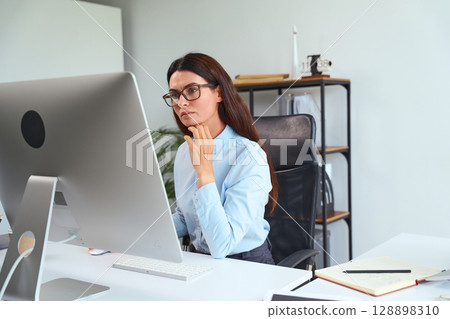 Focused Professional Woman Working on Computer at Office Desk in Modern Workspace 128898310