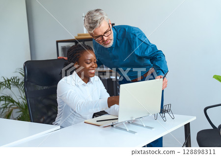 Professional Coworkers Collaborating On Office Work At Desktop Computer In Modern Workspace 128898311