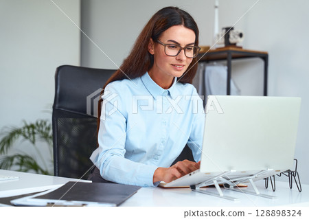 Professional Businesswoman Working on Laptop in Modern Office Environment Professional Businesswoman Working on Laptop in Modern Office Environment 128898324