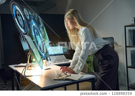Professional Woman Interacting With Futuristic Holographic Interface in a Modern Office Setting 128898359