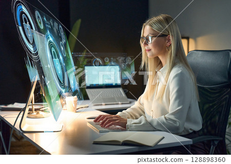 Professional Woman Analyzing Cybersecurity on Advanced Digital Interface Screen in Modern Office 128898360