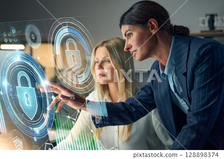 Two Professionals Working on Cybersecurity Solutions With Holographic Interface Screens Two Professionals Working on Cybersecurity Solutions With Holographic Interface Screens 128898374