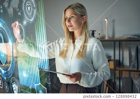 Young Professional Using Futuristic Touchscreen Display in Modern Office Environment Young Professional Using Futuristic Touchscreen Display in Modern Office Environment 128898432