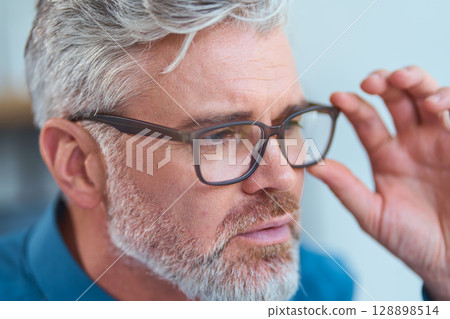 Mature Man Wearing Glasses Looking Thoughtful in a Close-Up Portrait Mature Man Wearing Glasses Looking Thoughtful in a Close-Up Portrait 128898514