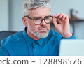 Focused Senior Professional Wearing Glasses Working on a Computer in a Modern Office 128898576