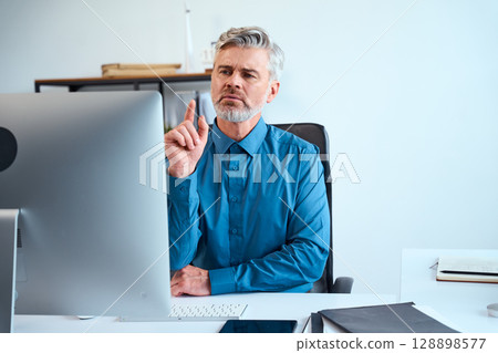 Confident Mature Businessman Thinking While Working at His Desk in a Modern Office 128898577