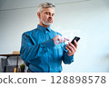 Man Using Smartphone with Futuristic Augmented Reality Interface in Office Environment 128898578