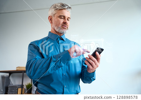 Man Using Smartphone with Futuristic Augmented Reality Interface in Office Environment 128898578