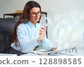 Businesswoman Analyzing Holographic Data Interface on High-Tech Digital Screen in Office 128898585