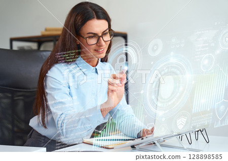 Businesswoman Analyzing Holographic Data Interface on High-Tech Digital Screen in Office 128898585
