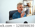 Professional Man Using Computer In Office With Focused Expression And Modern Attire 128898630