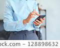 Professional Businesswoman Using Smartphone Indoors While Dressed in Formal Office Attire 128898632