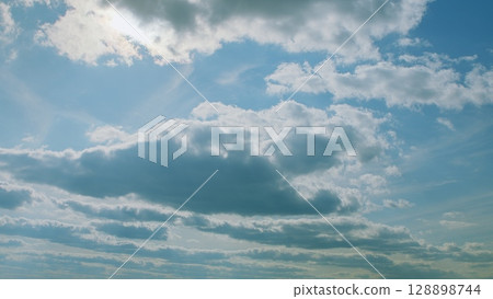 A Serene and Beautiful Blue Sky Adorned with Fluffy White Clouds on a Delightful Day 128898744