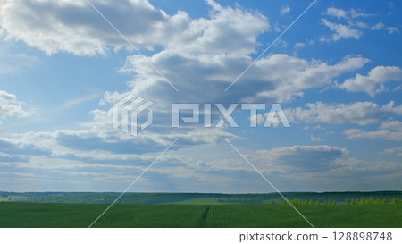 A Serene and Picturesque Landscape Featuring an Expansive Blue Sky with Fluffy White Clouds A Serene and Picturesque Landscape Featuring an Expansive Blue Sky with Fluffy White Clouds 128898748