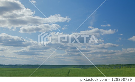 A Bright and Serene Blue Sky Spreads Across the Expansive Green Fields Below, Inviting Peace A Bright and Serene Blue Sky Spreads Across the Expansive Green Fields Below, Inviting Peace 128898789