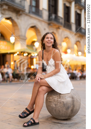 Woman sitting on a ball in the square of Barcelona 128899002