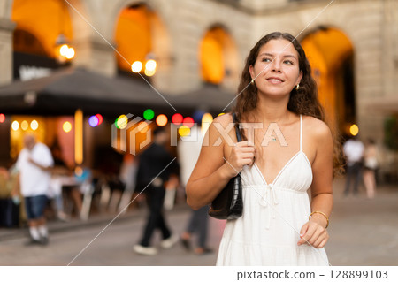 young woman walks through the evening streets of Barcelona 128899103