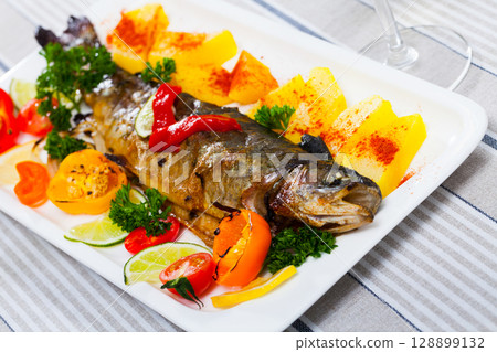 Grilled whole trout with vegetable garnish 128899132