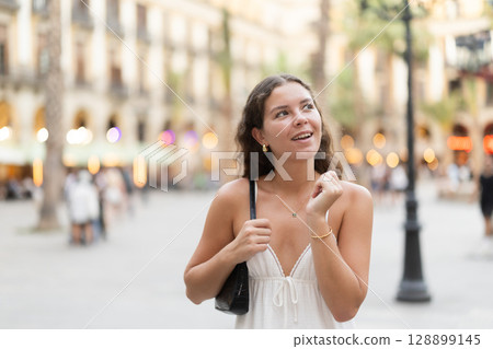 young woman walks through the evening streets of Barcelona 128899145