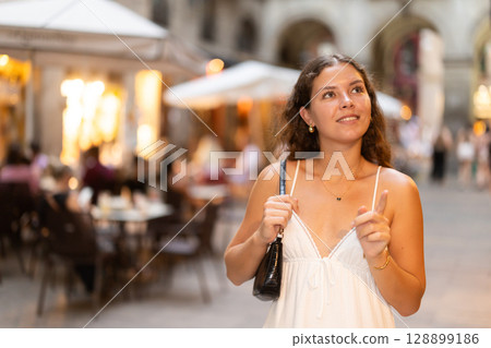young woman walks through the evening streets of Barcelona young woman walks through the evening streets of Barcelona 128899186