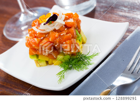 Cube of delicious salmon tartare garnish with avocado on plate at cafe 128899291